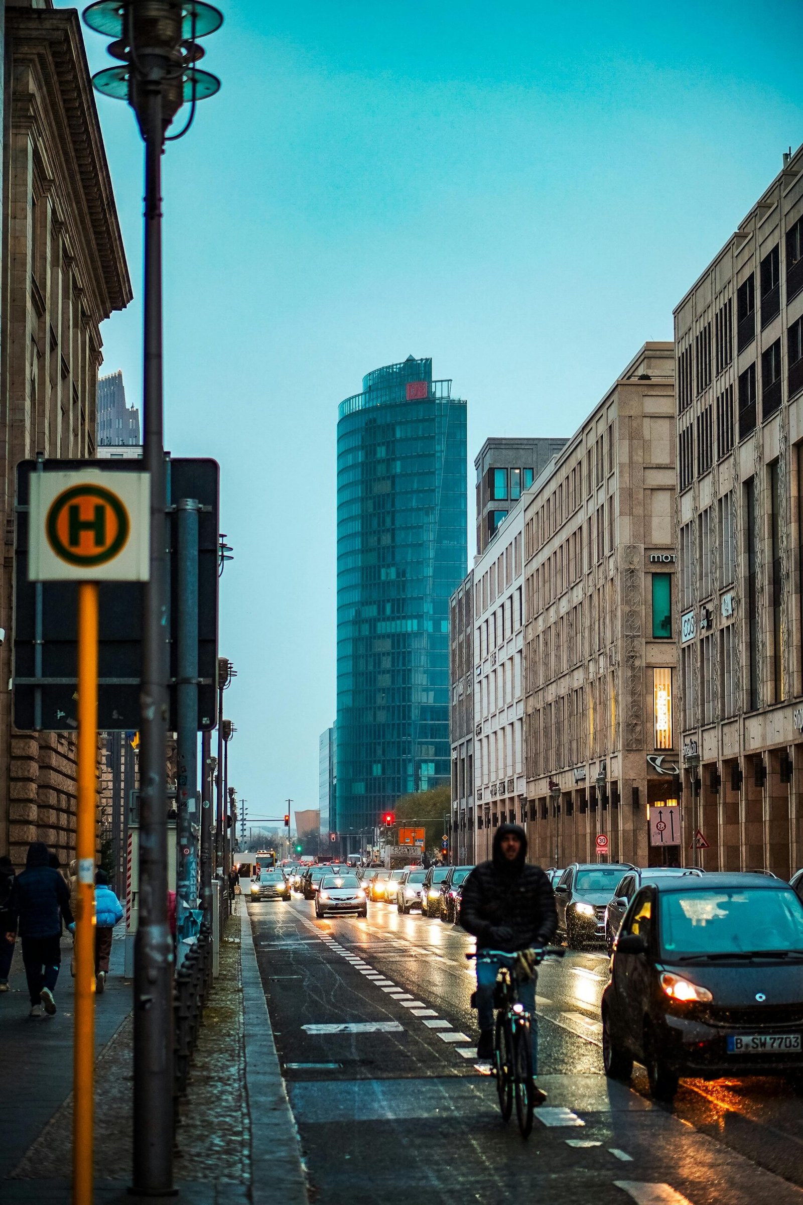 Urban evening view in Berlin with a cyclist and traffic on a busy street.